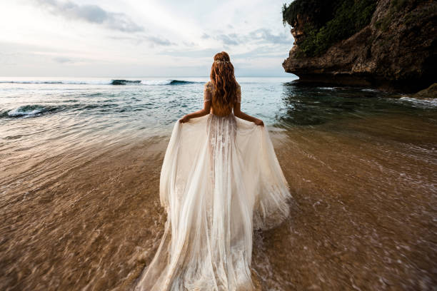 Newlyweds on the beach Bride in a white wedding dress comes into the sea water on the beach bride photos stock pictures, royalty-free photos & images