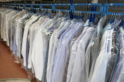 Freshly cleaned shirts and blouses in a textile cleanig, hangind on hangers and packed in plastic wrap.