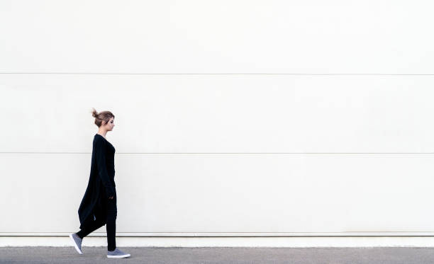 istock Young woman walking in front of white wall 1124848698