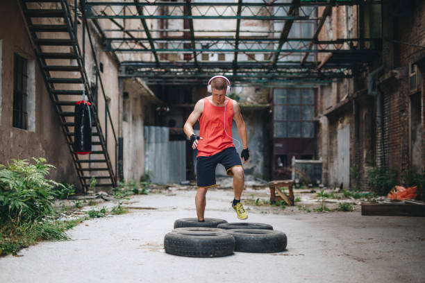 istock Athlete running over tires in an abandoned warehouse 1124855258