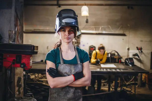 Young sisters working in their workshop together, welding and cutting things out of metal.