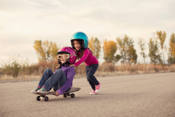 deux filles de course sur une planche à roulettes - pre adolescent child little girls friendship child photos et images de collection