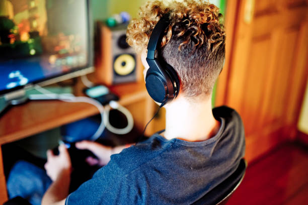 istock Over Shoulder View Teenage Boy Playing Games on his Desktop Computer 1124860077