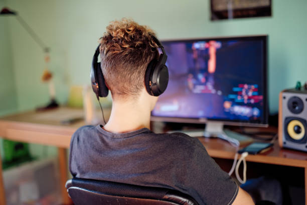 istock Rear View Teenage Boy Playing Computer Games on Desktop Computer 1124860080