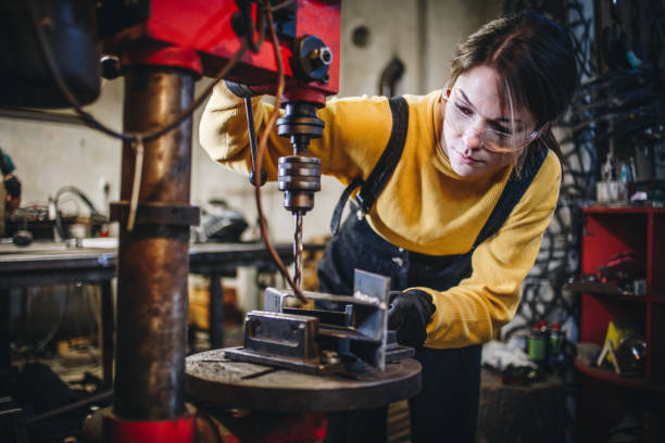 Young hard working woman drilling metal stock photo