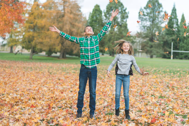 istock Siblings throwing leaves into the air at a park 1124870552