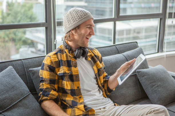istock Young man relaxing on sofa in modern living room using digital tablet wifi device 1124913184