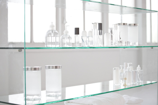 a lot of size and shape of glass bottles put on a glass shelf in a hygienic laboratory