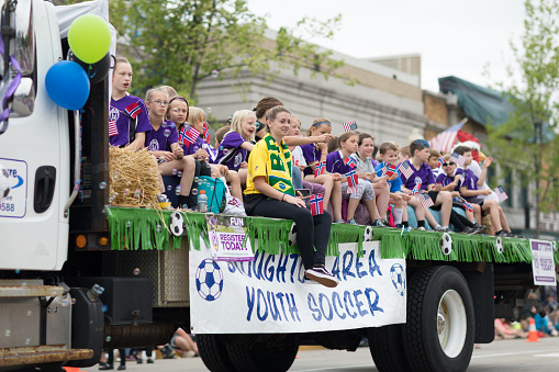 Stoughton, Wisconsin, USA - May 19, 2018: Syttende Mai Youth Parade, Children members of the Stoughton Area Youth Soccer, on a trailer, waving the american flag