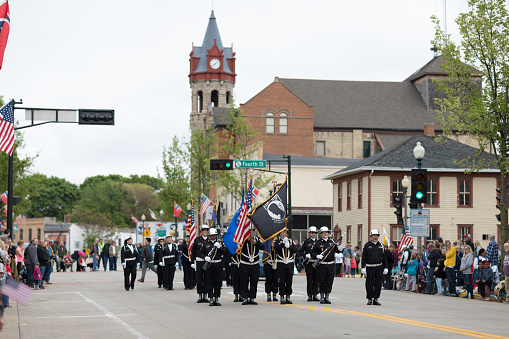 Stoughton, Wisconsin, USA - May 20, 2018: Annual Norwegian Parade, Men wearing military style uniforms, carrying the american flag, and one that says, POW, MIA, you are not forgotten