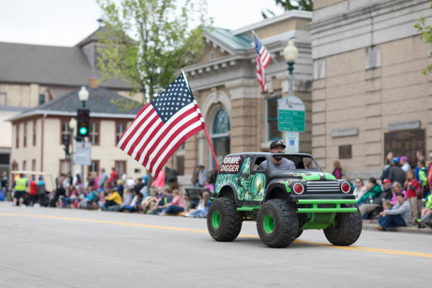 Norwegian Heritage Festival Stoughton, Wisconsin, USA - May 20, 2018: Annual Norwegian Parade, Man driving a mini monster truck, with a large american flag grave digger stock pictures, royalty-free photos & images