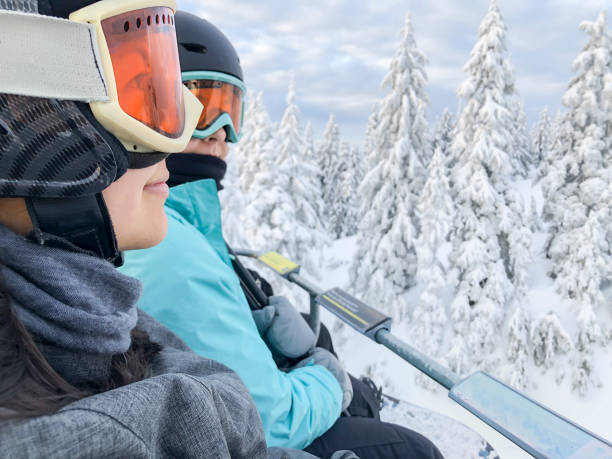 mixed_ethnic de esquí, snowboard hermanas montando aerosilla sobre nieve cubierto árboles - snowboarding snowboard women teenager fotografías e imágenes de stock
