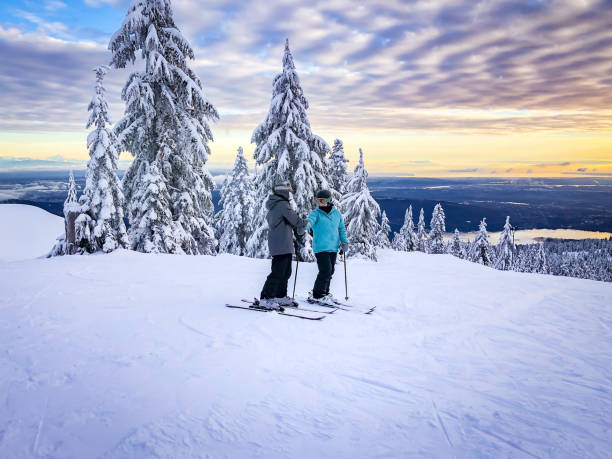 sciatori in cima alla pista da sci, vista al tramonto della città - snowboarding friendship snow winter foto e immagini stock