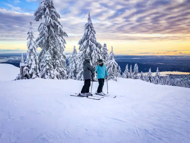 Photo of Skiers at Top of Ski Run, Sunset View of City