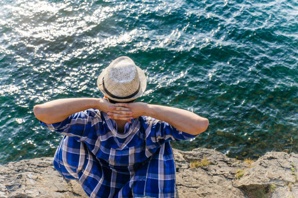 a portrait of a young male hiker is sitting and resting on a mounain
