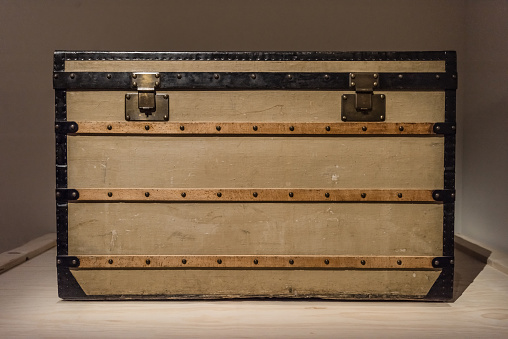 Leather travel suitcase placed on the antique old wooden wardrobe.