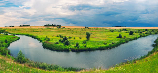 istock Cloudy summer landscape with golden fields,green meadows,woods and small river. 1124961804