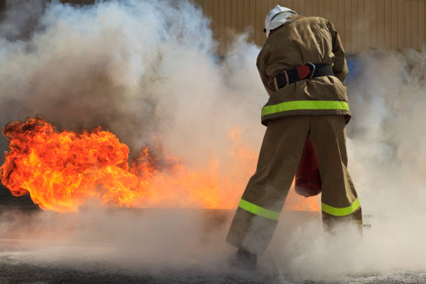 istock Extinguishing a major fire. A professional fireman in a special suit extinguishes an open fire with a fire extinguisher. 1124978276