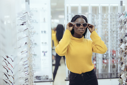 Young african woman wear sunglasses in optical shop