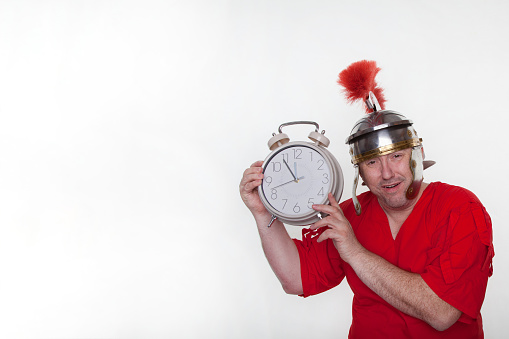 A roman soldier with a big alarm clock on the white background.
