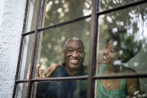 afro nonno latino ispanico e nipote che si abbracciano attraverso la finestra - grandparent adult smiling looking at camera foto e immagini stock