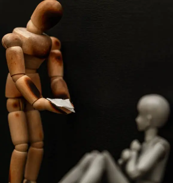 A damaged wooden mannequin offer a tissue to another who he believes needs some comforting.