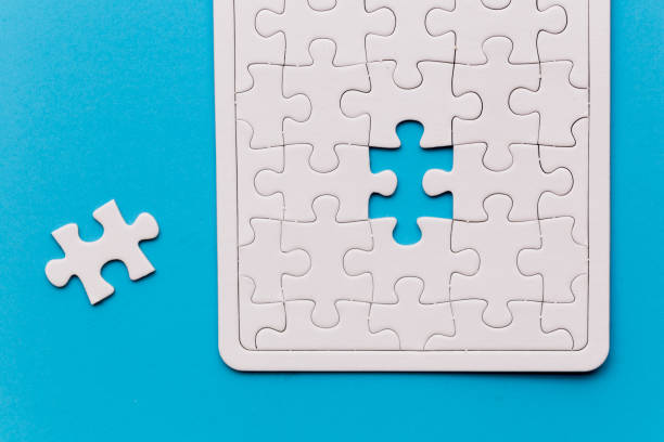 istock Unfinished white jigsaw puzzle pieces. One missing jigsaw piece on blue background 1124986198