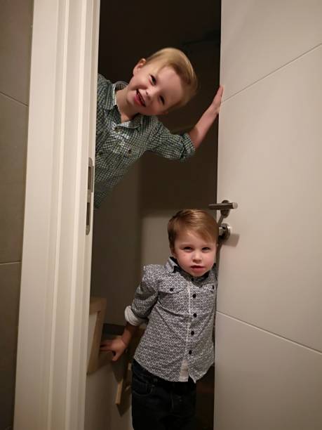 istock toddlers mischief, hiding behind door 1124989066