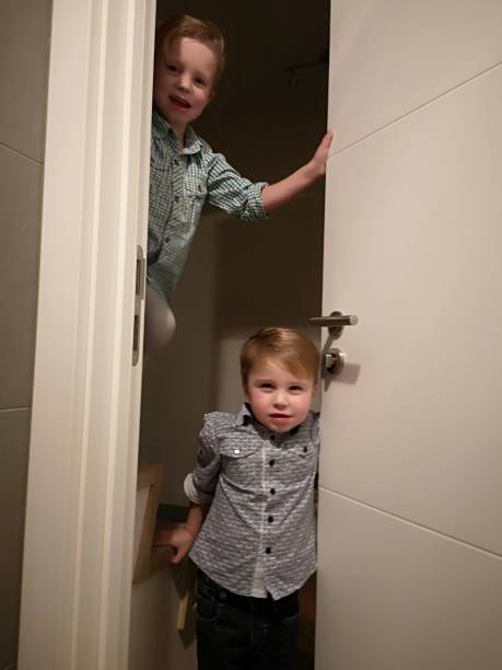 istock toddlers mischief, hiding behind door 1124989097