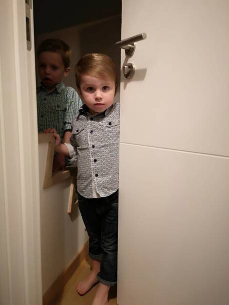 istock toddlers mischief, hiding behind door 1124989208