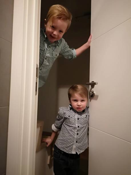 istock toddlers mischief, hiding behind door 1124989370