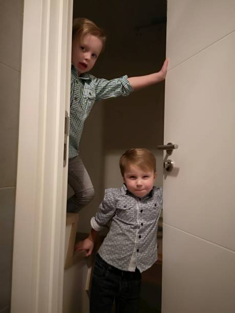 istock toddlers mischief, hiding behind door 1124989399
