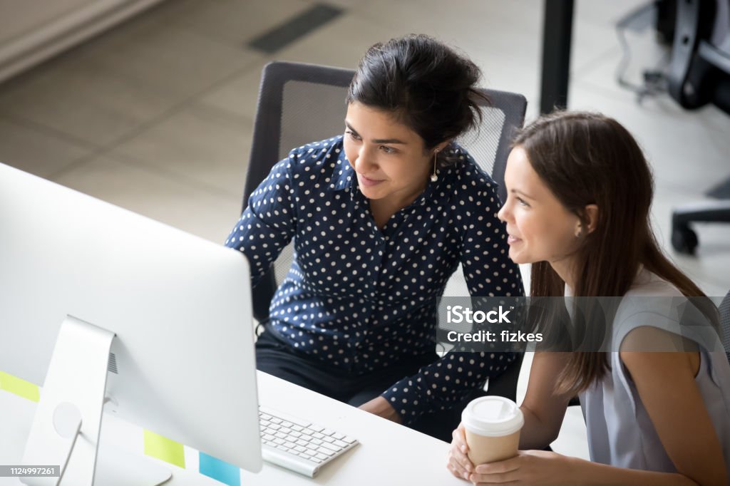 Multirraciales colegas sentados juntos mirando la pantalla del ordenador portátil en la oficina - Foto de stock de Aprendiz libre de derechos