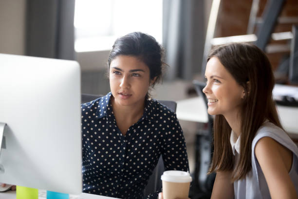 istock Multiracial colleagues sitting together looking at computer screen in office 1124997267