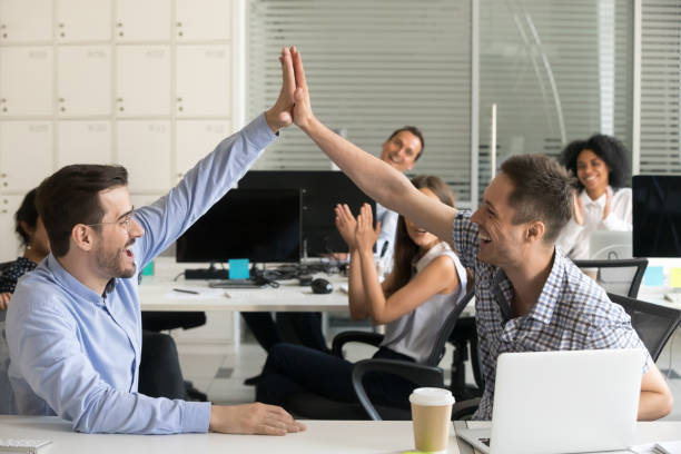 istock Excited office workers giving high five sitting at desk 1124997329