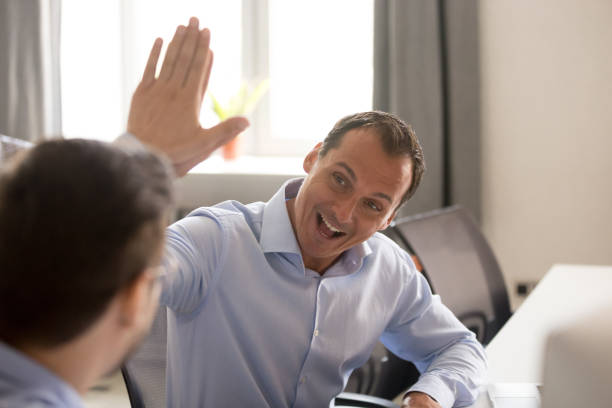 istock Office workers giving high five sitting at desk 1124997332