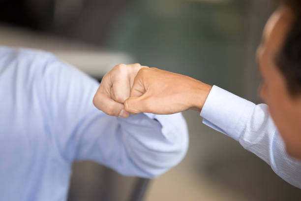 Close up male colleagues greeting fist bumping indoors Close up male colleagues workers fist bumping at business meeting celebrating good teamwork results or sharing success. Symbol of greeting, giving respect cooperation or approval, power five concept office buddies stock pictures, royalty-free photos & images