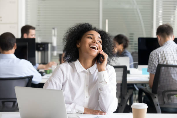 istock Black office worker sitting at desk talking by mobile phone 1124997383