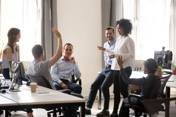 Team leader sharing ideas with colleagues in meeting Diverse team in coworking space voting some colleagues agree raises hands. Positive black leader woman with creative group of businesspeople discussing sharing ideas together in office at meeting evolution stock pictures, royalty-free photos & images