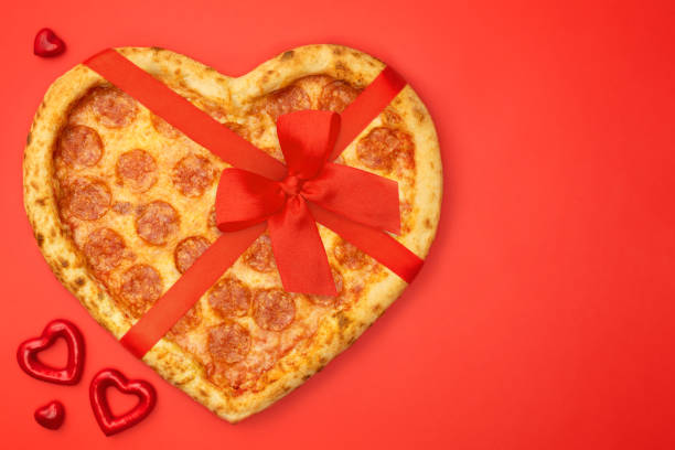 istock Pizza shaped heart with red bow ribbon for Valentine's Day romantic concept on red background 1124998749