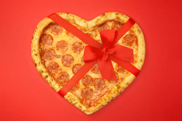 pizza en forma de corazón con cinta de lazo rojo para el concepto romántico de san valentín en fondo rojo - sausage shaped fotografías e imágenes de stock
