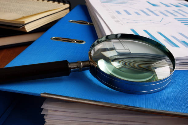 istock Magnifying glass and folder with pile of business documents. 1125002918