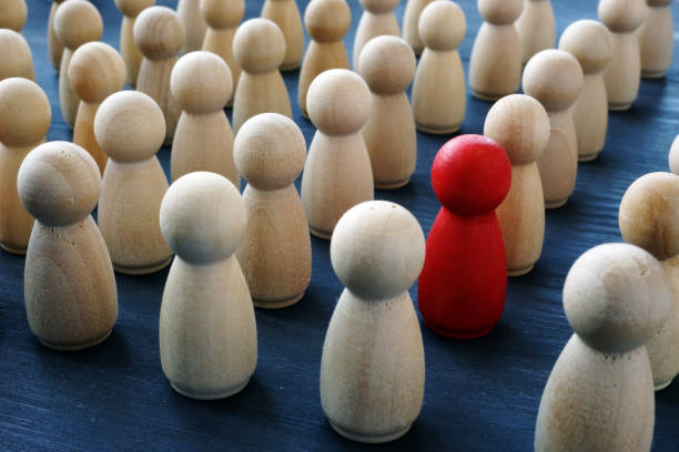 istock Uniqueness, individuality and difference. Red wooden figure in a crowd. 1125004110