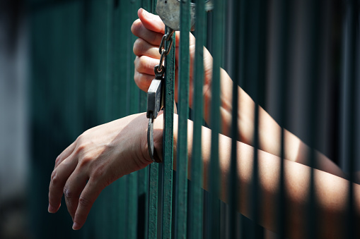 hand of prisoner in jail locked with handcuff