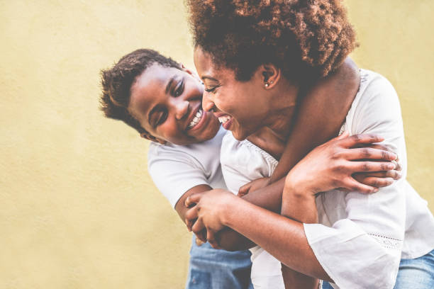 happy young mother having fun with her kid - son hugging his mum outdoor - family connection, motherhood, love and tender moments concept - focus on woman eye - child caribbean black latin american and hispanic ethnicity imagens e fotografias de stock