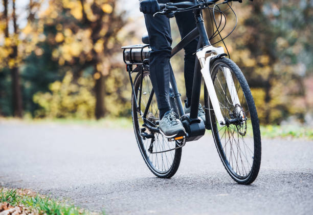 un homme méconnaissable sur electrobike vélo à l’extérieur sur une route dans le parc. - city bike photos et images de collection