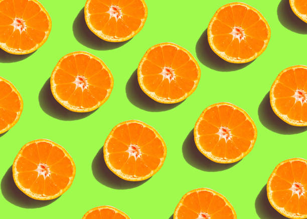 istock Colorful fruit pattern of fresh orange slices on green background. From top view 1125015538