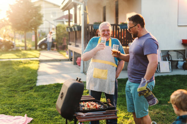 istock Cheerful father and son drinking beer while standing next to grill in backyard at summer. Family gathering concept. 1125017855
