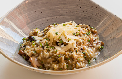 Risotto with mushrooms and cheese served in artisan earthenware.