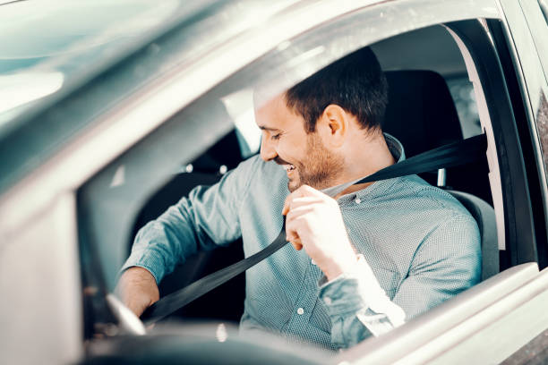 백인 남자 잠금 안전 벨트를 미소 하 고 그의 차에 앉아의 초상화. 창 연, 측면 보기입니다. - car door 이미지 뉴스 사진 이미지